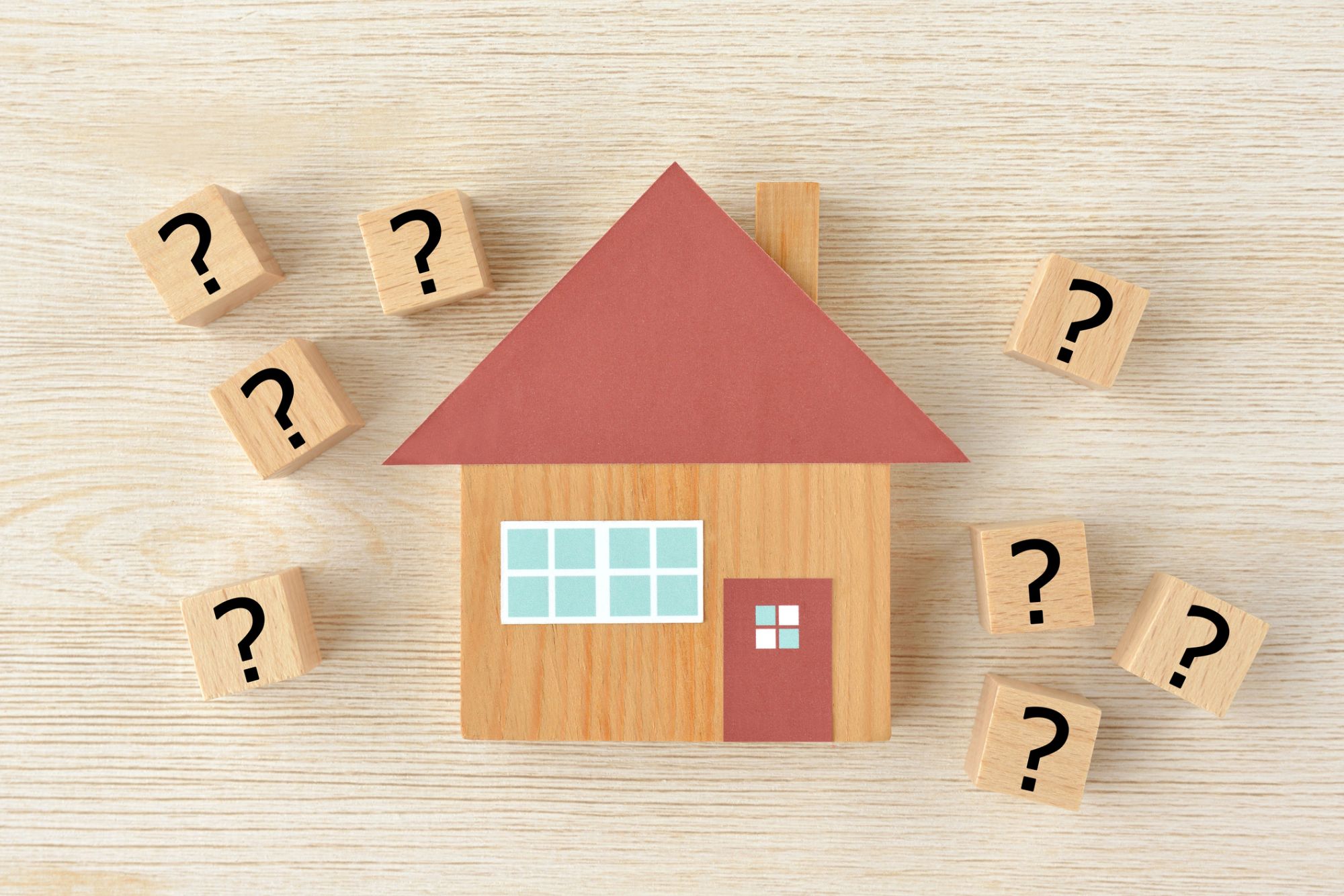 Holzhaus mit Fragezeichen-Würfeln – Fragen zur Immobilienbewertung