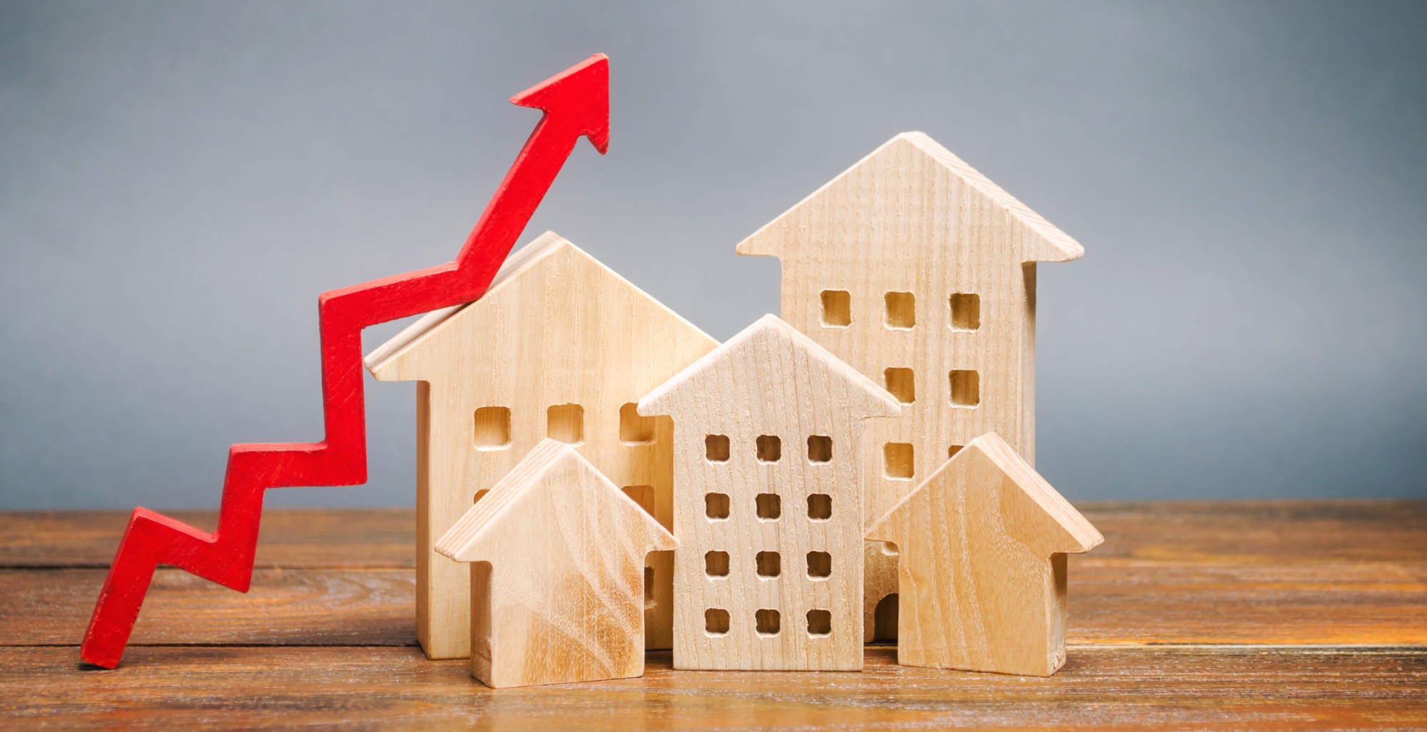 Holzhäuser mit rotem Pfeil – Entwicklung der Immobilienpreise