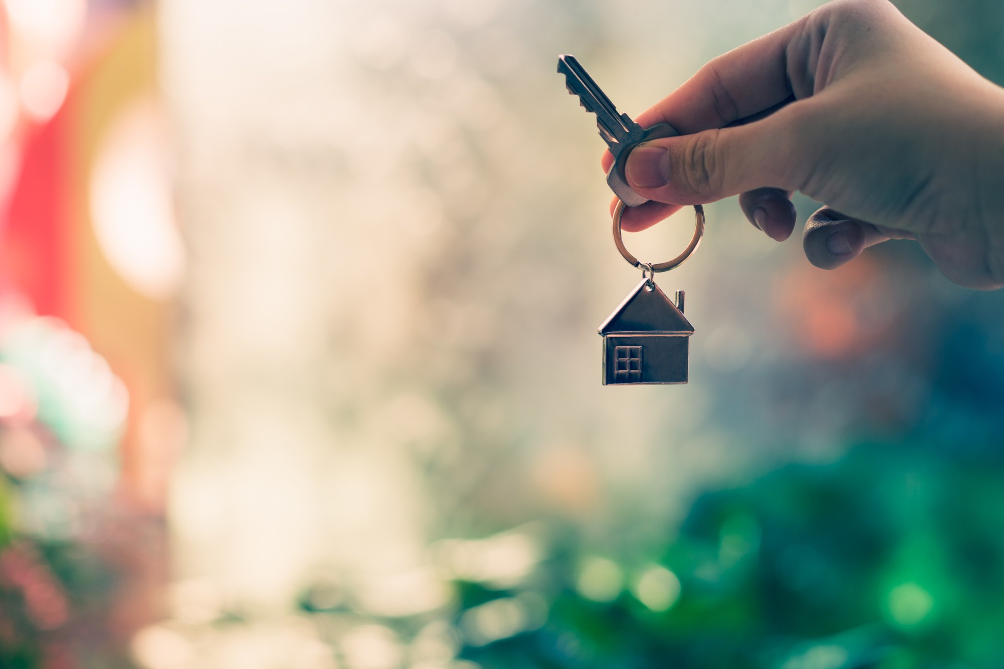 Hand hält einen Schlüssel mit Hausanhänger – Anlässe für eine Immobilienbewertung